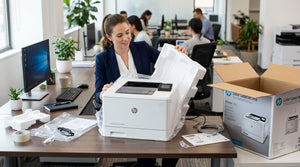 New laser printer on an office desk being unboxed, with packaging materials partially removed around it